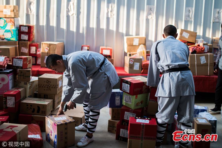 Wearing monk\'s robes, two Kung fu masters do a part time job as delivery man in Dengfeng city, Central China’s Henan province. With their special stunts of martial arts, the two can give a hand to local couriers in preparation for the approaching annual Singles Day online shopping extravaganza on November 11. (Photo/VCG)