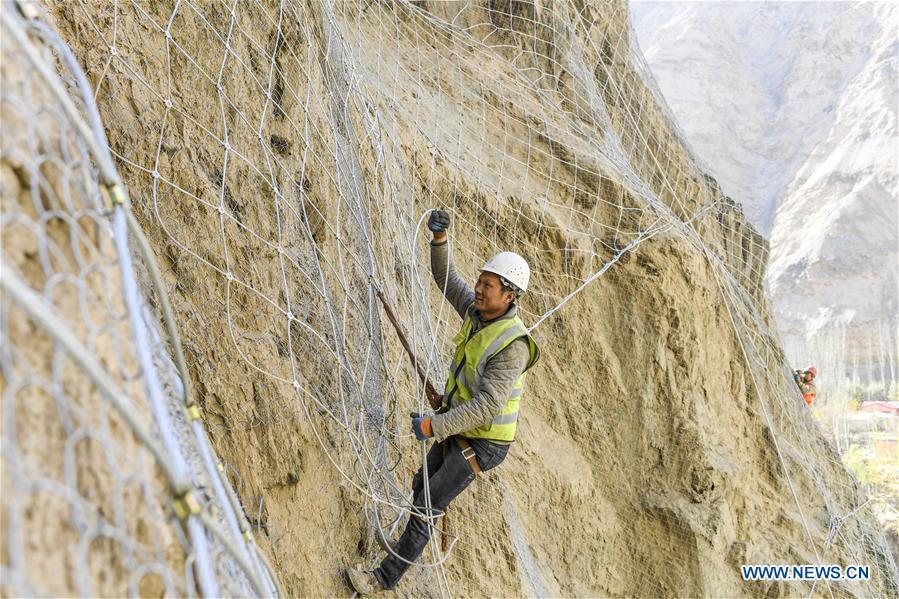 <?php echo strip_tags(addslashes(Construction worker Wu Fei installs protective nets on a cliff at a road section in the Tajik Autonomous County of Taxkorgan, northwest China's Xinjiang Uygur Autonomous Region, Nov. 12, 2018. The job of this team of construction workers is to install protective facilities on the cliff of risky road sections in the mountainous areas in Xinjiang, protecting pedestrians and vehicles from fallen stones. (Xinhua/Hu Huhu))) ?>
