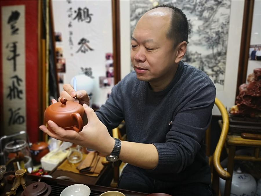 Zhao Qiushi creates the artworks of microscopic carving on a dark-red enameled pottery conditioner. (Photo/chinadaily.com.cn)