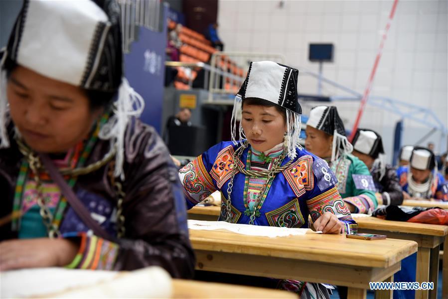 Competitors present wax printing skills during a manual skills competition held in Rongjiang County of Qiandongnan Miao and Dong Autonomous Prefecture, southwest China\'s Guizhou Province, on Nov. 15, 2018. A number of artisans from the county participated in the competition in aspects of spinning, weaving, wax printing, embroidery and so on. (Xinhua/Liu Jinyin)