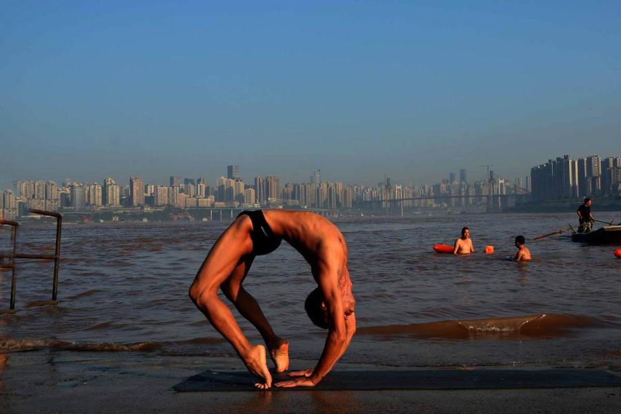 Wang Wanming, 61, a retiree in Southwest China\'s Chongqing municipality, has been practicing yoga almost every day by the Yangtze River for six years. His technique has made him a local celebrity. (Photo provided to chinadaily.com.cn)