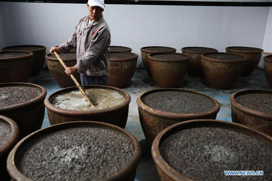 A worker stirs raw materials to make vinegar at a vinegar plant in Chishui, southwest China\'s Guizhou Province, Nov. 18, 2018. Chishui maintained a traditional method to make vinegar with over 30 process steps.(Xinhua/Wang Changyu)