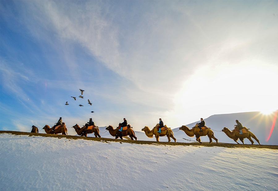 Dunhuang embraces this winter\'s first snowfall on Nov. 14. As the sun comes out, snow scenery in local landmark attractions like the Mingsha Mountain and Yueya Spring, a crescent-shaped spring-fed lake surrounded by desert, turns to a fairyland. (Photo/China Daily)