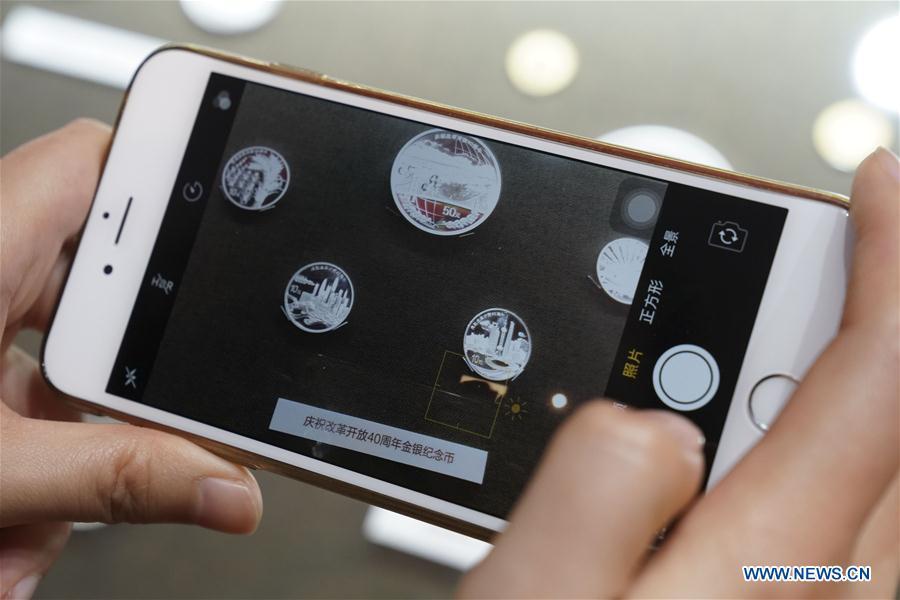 <?php echo strip_tags(addslashes(A visitor takes photos of commemorative coins displayed at a major exhibition to commemorate the 40th anniversary of China's reform and opening-up at the National Museum of China in Beijing, capital of China, Nov. 24, 2018. (Xinhua/Yin Gang))) ?>