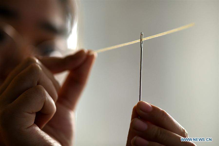 A worker demonstrates as he threads a needle with hollow noodle in a factory in Gengjiazhuang Village of Gaocheng District in Shijiazhuang, capital of north China\'s Hebei Province, Nov. 23, 2018. The fine dried noodle produced in Gongcheng, formerly article of tribute to the imperial family, is famous for its thin but hollow strings that is a result of more than ten working procedures. (Xinhua/Chen Qibao)