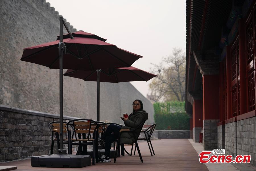 A girl enjoys her coffee at a café newly opened outside the Palace Museum\'s Shenwu Men, or the Gate of Divine Might in Beijing on December 1, 2018. Named “Café by The Forbidden City”, the coffee shop in the theme of imperial China enables their customers to enjoy a wide range of drinks while experiencing ancient Chinese culture.  (Photo: China News Service/ Du Yang)