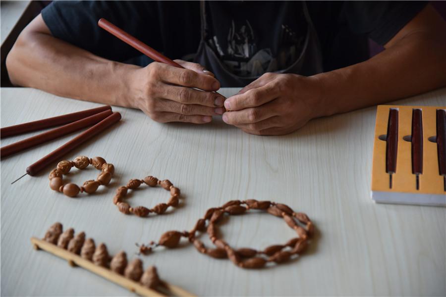 Zhu Haiyang does olive pit carving at his home in September of last year.  (Photo by Qian Lei for chinadaily.com.cn)