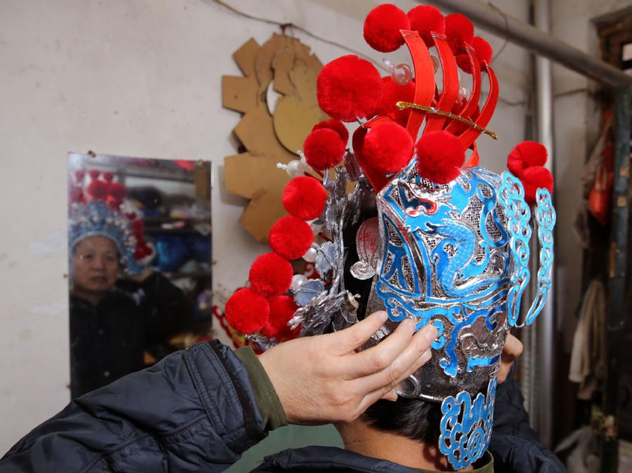Han Xiaoli tries on a headdress he made. (Photo by Huo Yan/chinadaily.com.cn)