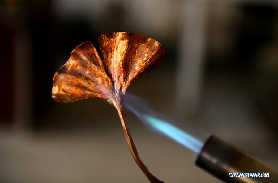 Guo Hailong, inheritor of welding-aided iron relief handicraft, makes an iron ginkgo leaf at his workshop in Deming ancient town of Shijiazhuang, capital of north China\'s Hebei Province, on Dec. 4, 2018. The craftsmanship was listed as the provincial intangible cultural heritage in 2013. (Xinhua/Chen Qibao)