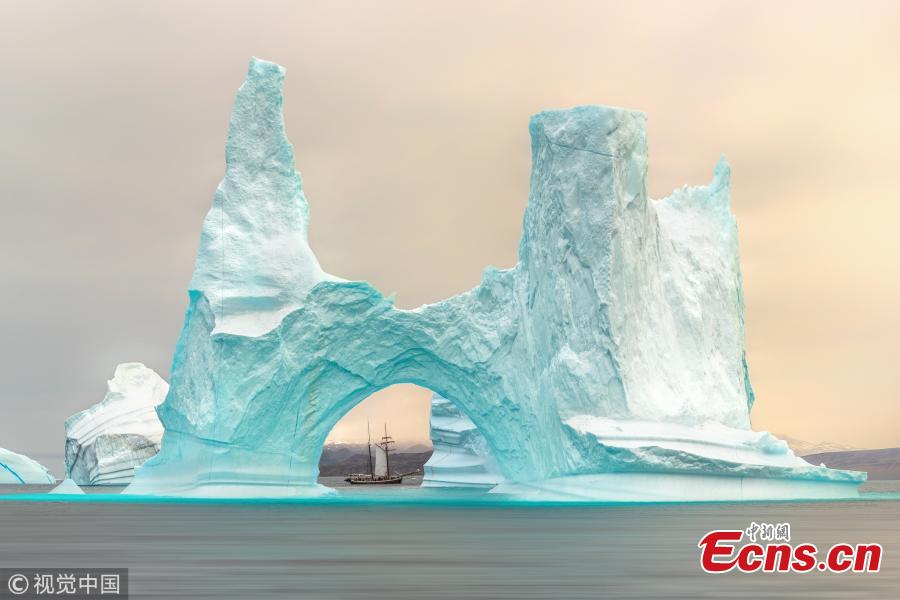 British photographer James Rushworth captured the moment when a schooner passed by a giant iceberg off the east coast of Greenland. The 108-foot-long schooner was dwarfed by the 300-foot-tall turquoise iceberg. The 32-year-old photographer braved temperature of minus 10 degrees Celsius as he waited for the vessel to reach the center of the arch of the iceberg. (Photo/VCG)