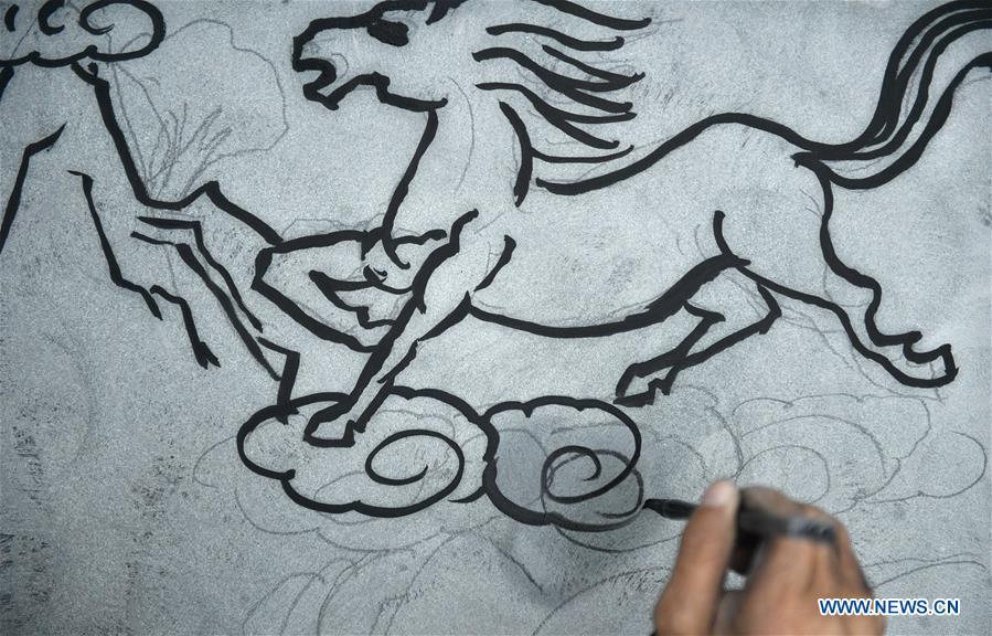 A handicraftsman sketches on a rock carving work for further processing in Longdong Village of Xuan\'en County in Enshi Tujia and Miao Autonomous Prefecture, central China\'s Hubei Province, Dec. 5, 2018. Residents here benefit from the rich rock resources and turn plain rocks into delicate artworks. (Xinhua/Song Wen)