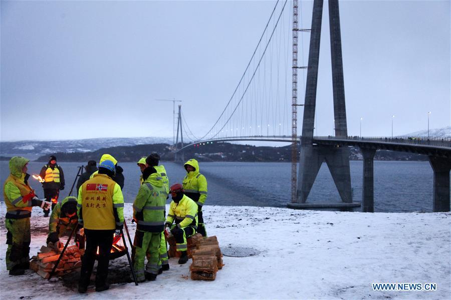 Chinese workers get warm by the fire beside the Halogaland Bridge near Norway\'s northern port city of Narvik, Dec. 9, 2018. A ceremony was held Sunday to officially open Norway\'s second largest bridge that has been built by a Chinese company and its partners some 220 km inside the Arctic Circle. With a total length of 1,533 meters and a free span of 1,145 meters, the Halogaland Bridge near Norway\'s northern port city of Narvik is the longest suspension bridge within the Arctic Circle. (Xinhua/Liang Youchang)