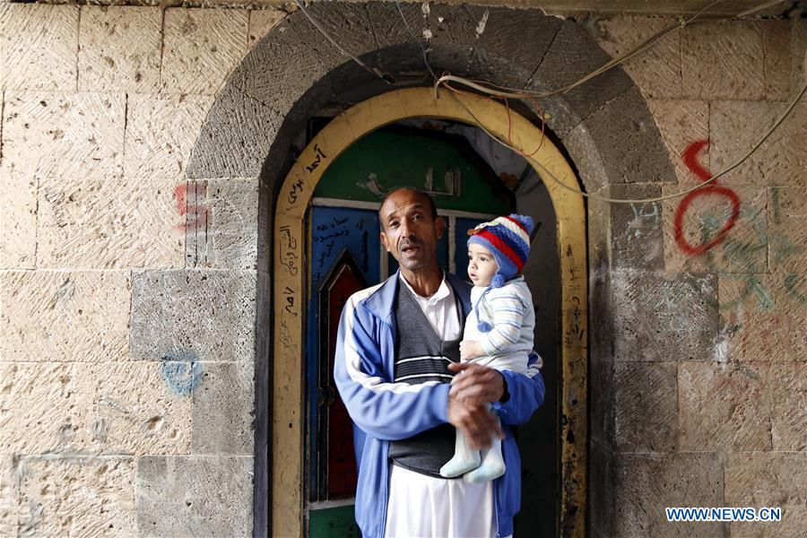 <?php echo strip_tags(addslashes(Ahmed al-Sharafi holding his seven-month-old child Omar stands at the door of his house in Sanaa, Yemen, on Dec. 9, 2018. An estimated 85,000 children under the age of five may have died from extreme hunger between April 2015 and October 2018, according to the latest data released by Save the Children, an international organization for children's rights. (Xinhua/Mohammed Mohammed))) ?>