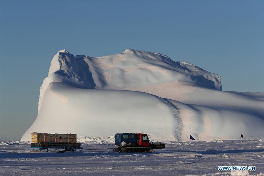 A snowmobile passes by an iceberg as it transports supplies to the Zhongshan Station in Antarctica, Dec. 5, 2018. China\'s 35th Antarctic research expedition team finished the first phase of unloading supplies operation on Friday. A total of 1,605 tons of supplies have been transported from China\'s research icebreaker Xuelong to the destination. (Xinhua/Liu Shiping)