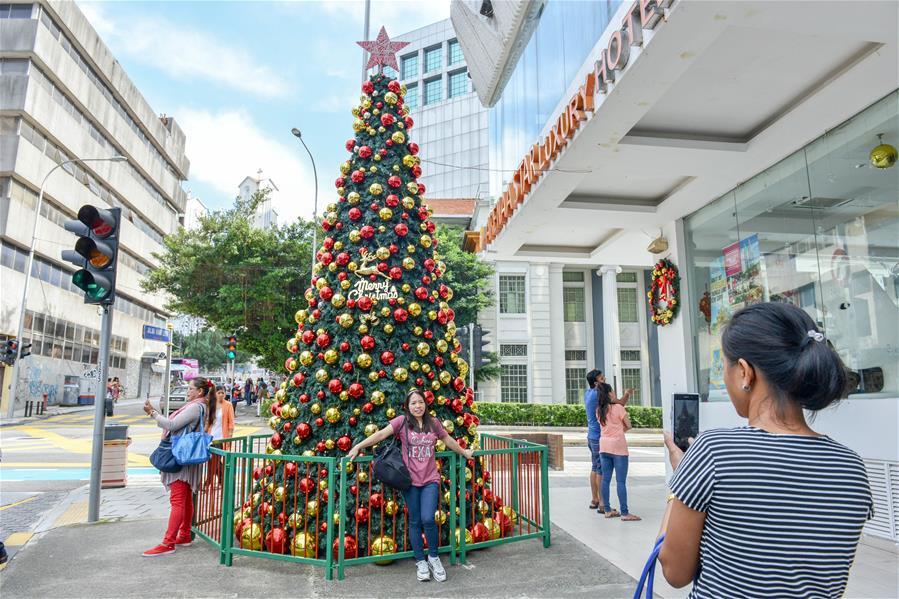 People pose for photos with a Christmas tree in Kuala Lumpur, Malaysia, on Dec. 16, 2018. (Xinhua/Chong Voon Chung)