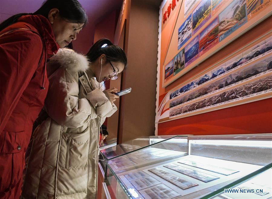 People look at the stamps displayed during a major exhibition to commemorate the 40th anniversary of China\'s reform and opening-up at the National Museum of China in Beijing, capital of China, Dec. 22, 2018. The exhibition has received more than 1.85 million visitors since its opening. (Xinhua/Li He)