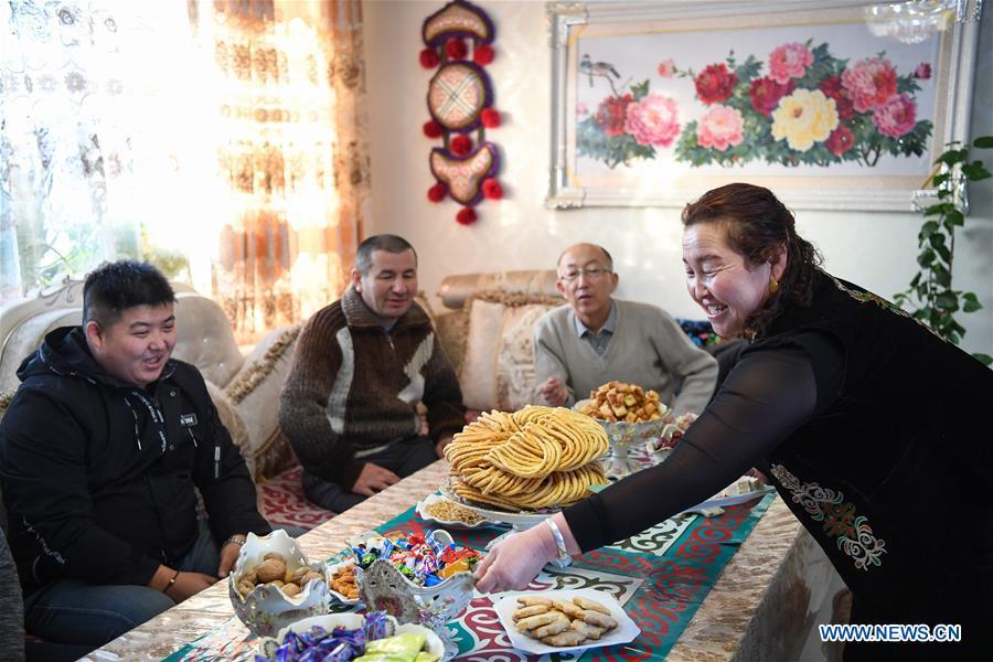 A hostess (R) of local accommodation serves guests in Burqin County, northwest China\'s Xinjiang Uygur Autonomous Region, Dec. 22, 2018. Burqin County, home to the region\'s renowned Kanas Lake, which takes tourism as its pillar industry speeds up the development of local tourism from single scenic spot to holiday resort in recent years. (Xinhua/Liu Dawei)