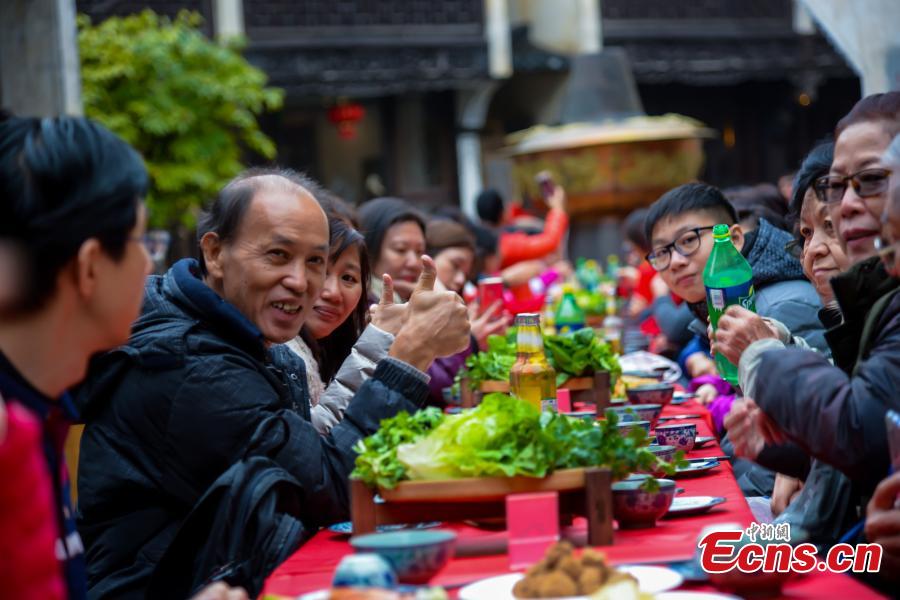 A hot-pot banquet is held on a street in Huangling Ancient Village in Wuyuan County, East China\'s Jiangxi Province, Dec. 22, 2018. The centerpiece of the long-table banquet, a traditional manner in which to celebrate some major festivals and entertain guests, is a giant copper pot measuring three meters in height and two meters in diameter. Visitors, including some from Singapore and Malaysia, joined the feast, where the tables extended for 100 meters. (Photo: China News Service/Fang Huabin)