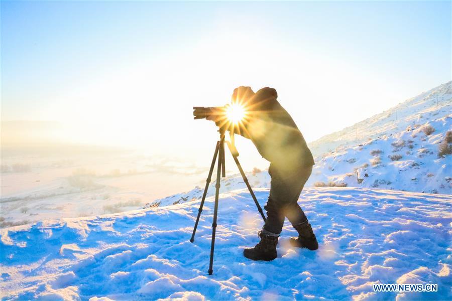 A photographer takes photos at Chonghuer Town in Burqin County, northwest China\'s Xinjiang Uygur Autonomous Region, Dec. 22, 2018. Burqin County, home to the region\'s renowned Kanas Lake, which takes tourism as its pillar industry speeds up the development of local tourism from single scenic spot to holiday resort in recent years. (Xinhua/Sadat)