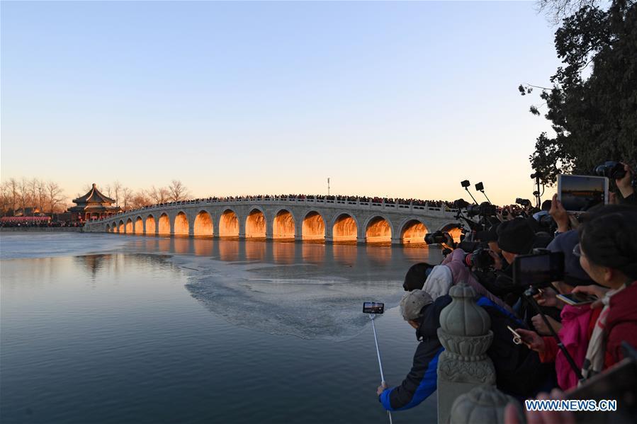 Visitors and photographers take photos of the Qikong Bridge with sunset glow shining through its holes at the Summer Palace in Beijing, capital of China, Dec, 23, 2018. (Xinhua/Chen Yehua)