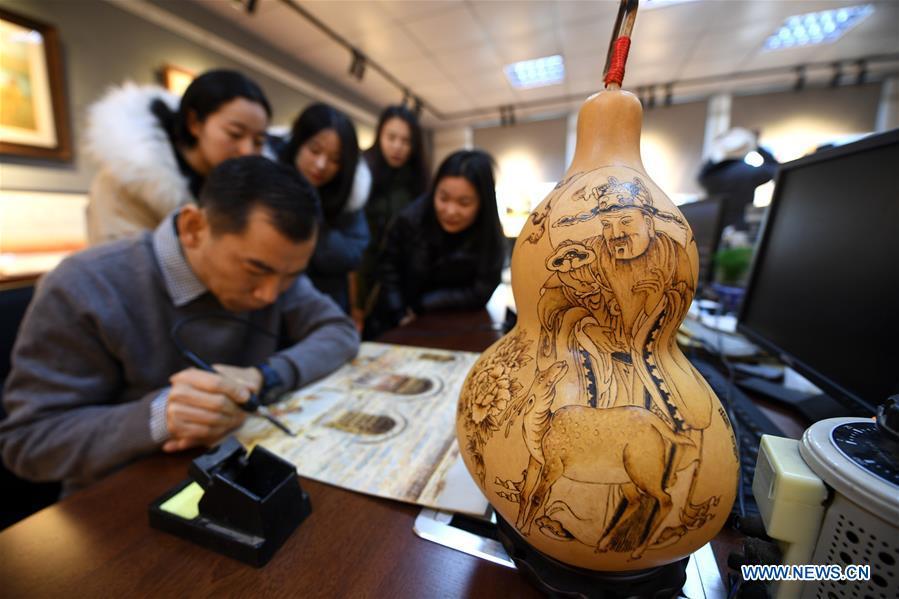 Zhang Pengjun (1st L) teaches students the technique of pyrograph at Hebei College of Industry and Technology in Shijiazhuang, north China\'s Hebei Province, Dec. 28, 2018. The college takes intangible cultural heritages such as techniques of pyrograph and inner painting into school courses in recent years. (Xinhua/Xue Dongmei)
