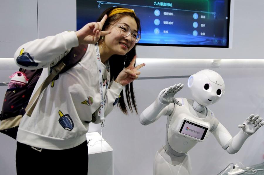 A robot imitates a visitor\'s pose at PT Expo, a telecom exhibition that opened in Beijing on Sept. 26, 2018. (Photo/China Daily)