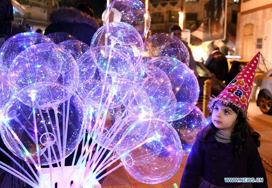 A Syrian girl looks at balloons on the New Year\'s Eve in Damascus, Syria, Dec. 31, 2018. (Xinhua/Ammar Safarjalani)