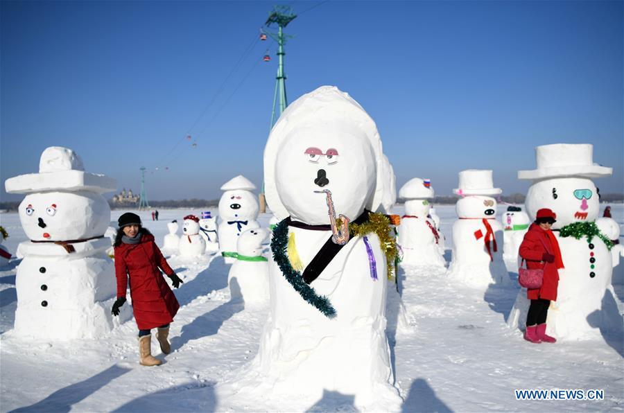 People pose for photo with snowman sculptures on the riverbank of Songhua River in Harbin, capital of northeast China\'s Heilongjiang Province, Jan. 2, 2019. Altogether 2,019 cute snowmen were displayed here to greet the year 2019. (Xinhua/Wang Jianwei)