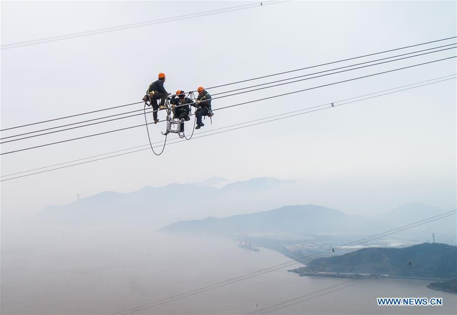 Staff members work on the cables at the site of the giant power supply pylons in Zhoushan, east China\'s Zhejiang Province, Jan. 3, 2019. The two 380-meter-tall pylons carry power cables between Zhoushan\'s Jintang and Cezi islands, a distance of 2,656 meters. The new pylon project is a part of a new ultra-high voltage power line project between cities of Zhoushan and Ningbo. (Xinhua/Xu Yu)