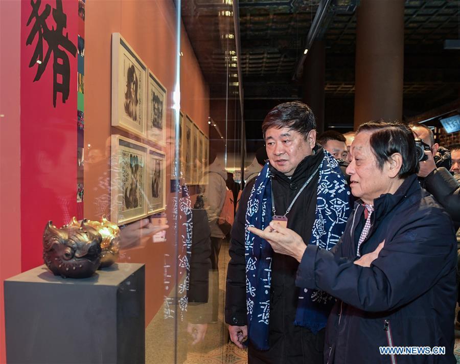 Chinese artist Han Meilin (R) introduces his art works to Shan Jixiang, curator of the Palace Museum, during Han Meilin\'s Chinese Zodiac Art Exhibition in Beijing, capital of China, Jan. 5, 2019. The Chinese Zodiac Art Exhibition, displaying the fine arts of Chinese artist Han Meilin, kicked off in the Palace Museum on Saturday and will last until Feb. 20, 2019. (Xinhua/Li He)