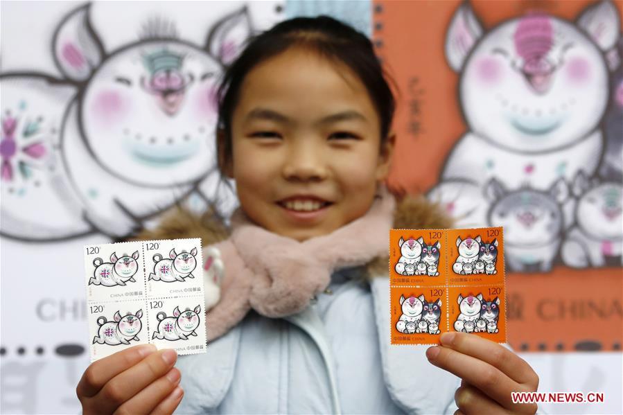 A kid presents special zodiac stamps for the lunar year of the Pig in Huangshan City, east China\'s Anhui Province, Jan. 5, 2019. China Post on Saturday issued a set of special zodiac stamps in honor of 2019 Chinese Lunar New Year, or the Year of the Pig. The Year of the Pig starts from Feb. 5, 2019. (Xinhua/Shi Yalei)