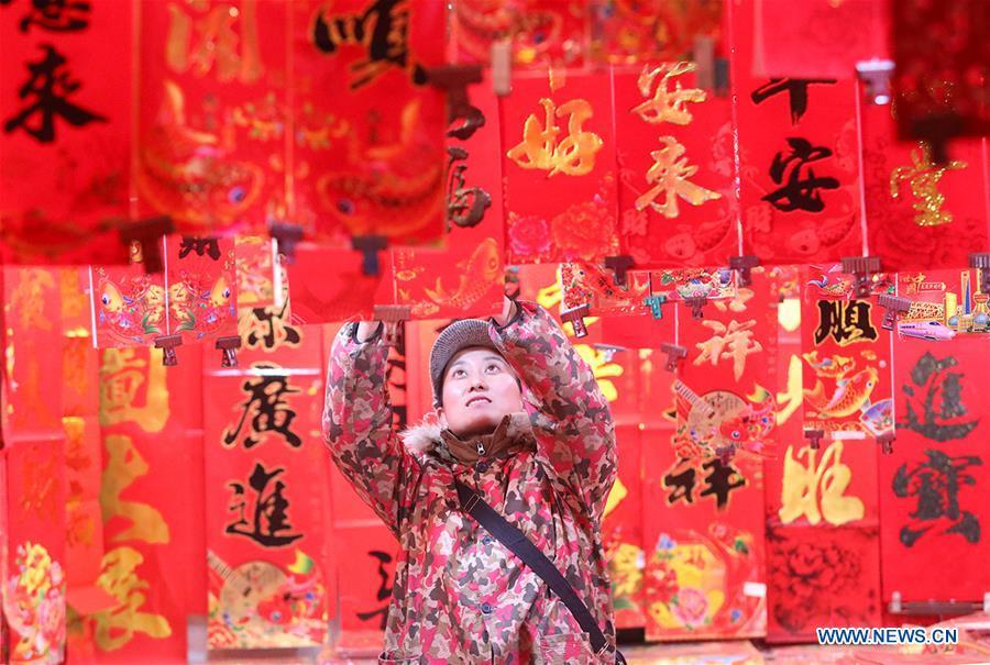 A seller arranges newly arrived Spring Festival couplets at a market in Shijiazhuang, north China\'s Hebei Province, Jan. 6, 2019. People are busy buying decorations such as Spring Festival couplets and lanterns to greet the upcoming Lunar New Year. (Xinhua/Liang Zidong)
