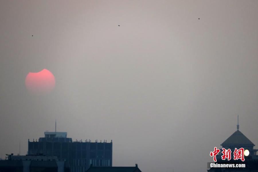 A partial solar eclipse is observed next to the Forbidden City in Beijing, Jan. 6, 2019. (Photo: China News Service/Sun Zifa)