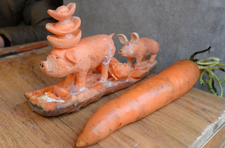 An ordinary carrot and a sculpture made of the same material by Guo Yuhong, a vegetable vendor. (Photo by Hao Qunying for chinadaily.com.cn)