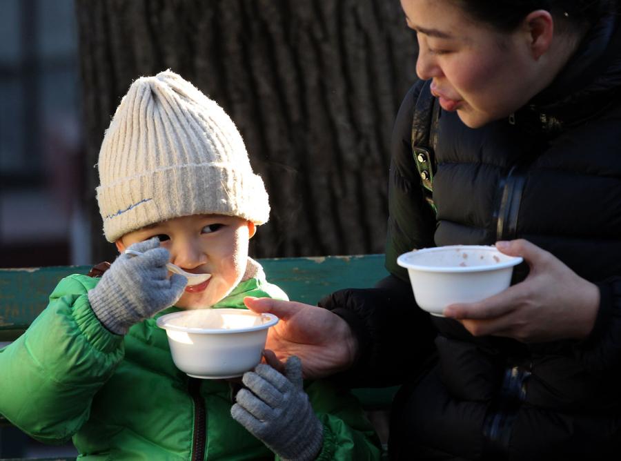 Visitors and tourists taste Laba porridge at Yonghe Temple, Beijing, on Jan. 13, 2019. (Photo/China Daily)