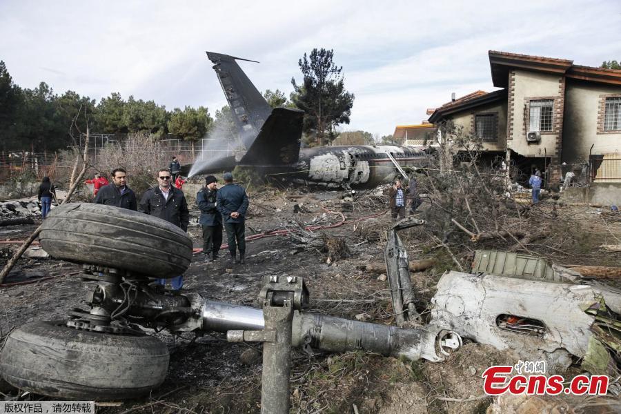 People gather amid the debris of a Boeing 707 cargo plane that reportedly crashed into a residential complex near the Iranian capital Tehran with more than 10 people onboard on January 14, 2019. The plane overshot the runway during its landing, Iran\'s aviation organisation spokesman Reza Jafarzadeh told state broadcaster IRIB. (Photo/Agencies)