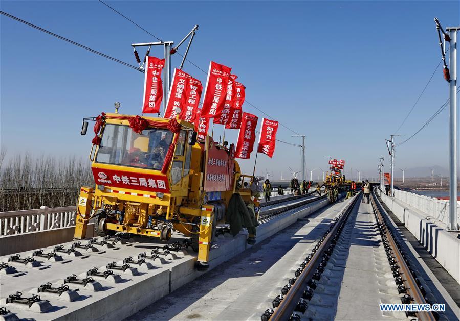 Workers lay the tracks for the Beijing-Zhangjiakou high-speed railway line at Guanting Reservoir grand bridge in north China\'s Hebei Province, on Jan. 13, 2019. Track laying work of the Beijing-Zhangjiakou high-speed railway line at Guanting Reservoir grand bridge was completed on Sunday. The 174-km-long railway, connecting China\'s capital Beijing and Zhangjiakou of north China\'s Hebei Province, is a major transportation project for the 2022 Winter Olympic Games. (Xinhua/Yang Shiyao)