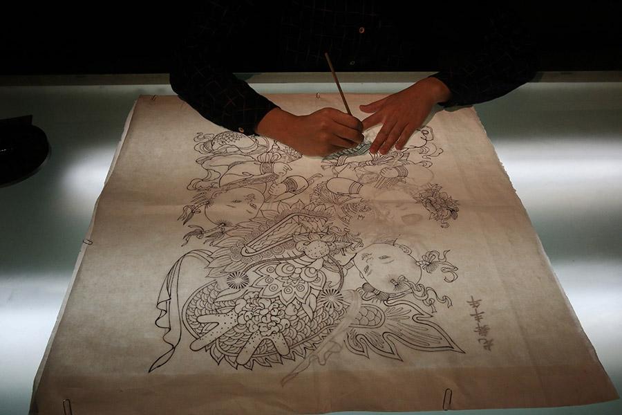 A woman is seen working on a traditional Yangliuqing woodblock printing. (Photo/chinadaily.com.cn)