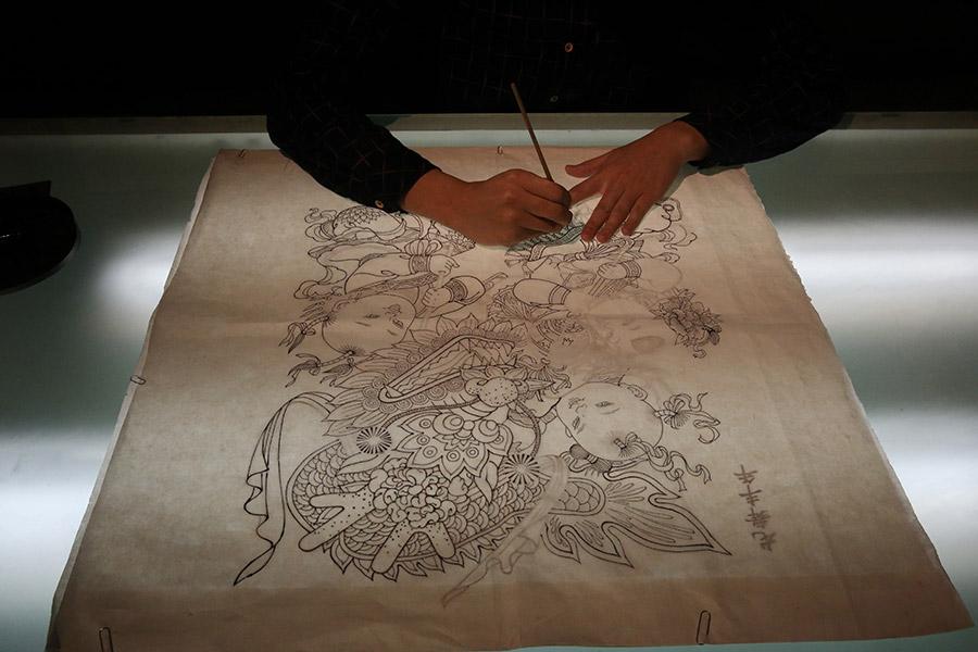 A woman is seen working on a traditional Yangliuqing woodblock printing.  (Photo/chinadaily.com.cn)