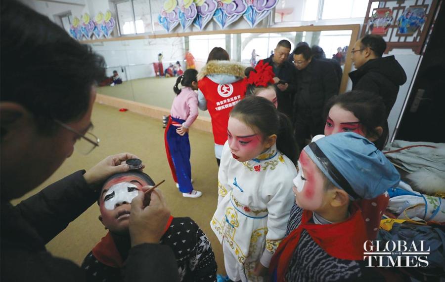 Li Pengshan, an instructor with the Peking Opera Association, applies face paint on students. (Photos: Yang Hui/GT)