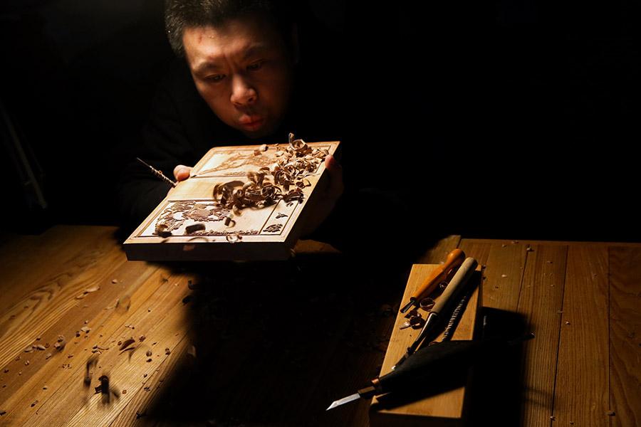 A man is seen working on a traditional Yangliuqing woodblock printing. (Photo/chinadaily.com.cn)