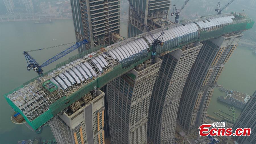 <?php echo strip_tags(addslashes(Core construction work on a 300-meter-long conservatory, part of the Raffles City Chongqing complex, is complete in Southwest China's Chongqing, Jan. 14, 2019. Located at the confluence of the Yangtze and Jialing rivers, Raffles City Chongqing has been designed by world-renown architect Moshe Safdie, who drew inspiration from the region's thousand years of waterway transportation history. The conservatory, 32.5 meters wide and 26.5 meters tall, connects the tops of four buildings, 250 meters above the ground, as well as accommodating a viewing deck, an infinity pool, a sky walk and varied dining options. (Photo provided to China News Service))) ?>