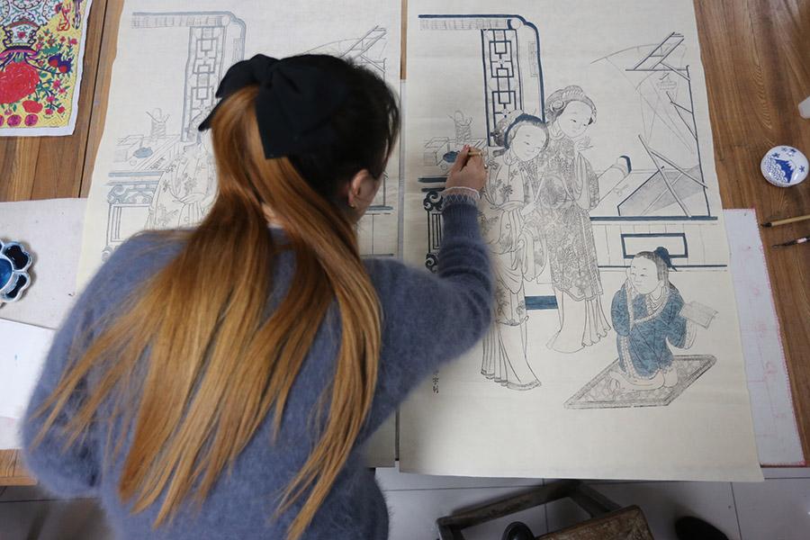 A woman is seen working on a traditional Yangliuqing woodblock printing. (Photo/chinadaily.com.cn)
