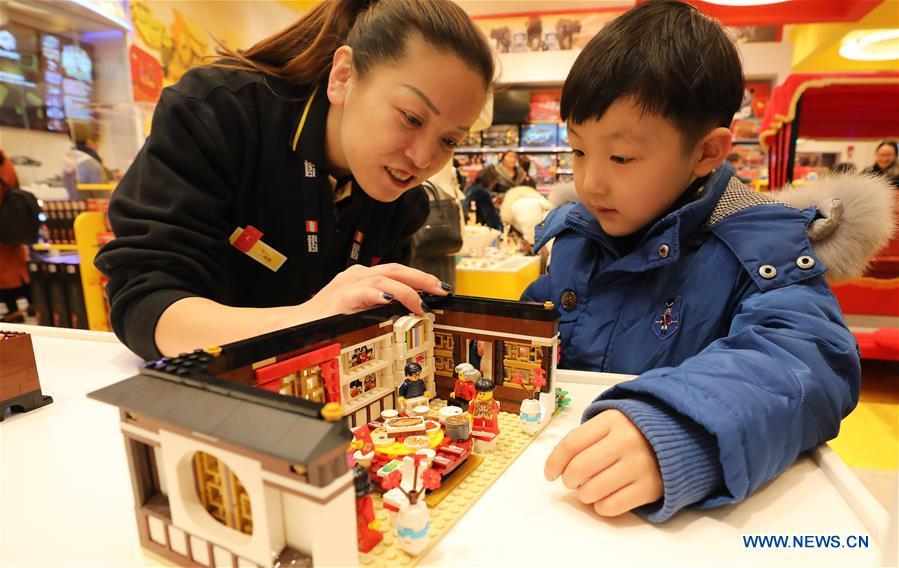 A vendor explains as a child looks at the toy bricks that is designed with the theme of new year\'s eve dinner to coincide with the Spring Festival at a store in east China\'s Shanghai, Jan. 14, 2019. (Xinhua/Fang Zhe)