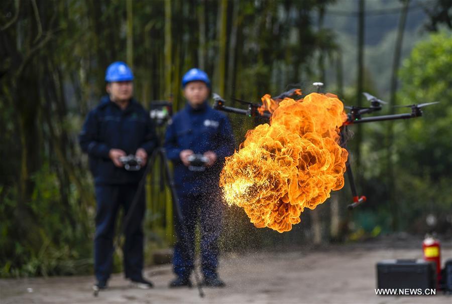 A flame-spurting drone destroys a hornet\'s nest on a wire pole in Xiaokan Village of Chongqing, southwest China, Jan. 16, 2019. The drone was developed by Chongqing\'s Yongchuan company of the State Grid corporation to help clear harmful obstacles hanging on overhead wires. (Xinhua/Liu Chan)