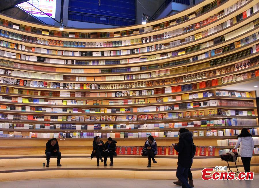 A circular wall stacked with books at a new bookstore in Hohhot, North China\'s Inner Mongolia Autonomous Region, Jan. 20, 2019. The innovative wraparound shelving units have attracted the interest of many visitors. (Photo: China News Service/Chen Feng)