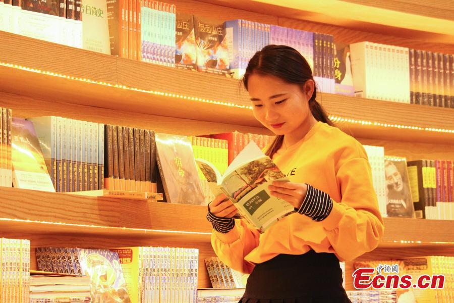 A circular wall stacked with books at a new bookstore in Hohhot, North China\'s Inner Mongolia Autonomous Region, Jan. 20, 2019. The innovative wraparound shelving units have attracted the interest of many visitors. (Photo: China News Service/Chen Feng)