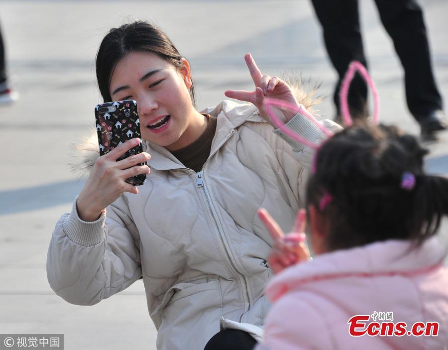 A mother takes a picture of her daughter at a railway station in Shanghai. (Photo/VCG)
