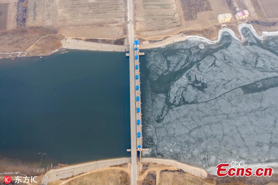 A view of a dam on the Majia River in Wudi County, East China\'s Shandong Province, Jan. 24, 2019. The horse cheek-shaped river dates back to the legendary Yu the Great some 4,000 years ago. Because of a water conservation project, the water is frozen on just one side. (Photo/IC)