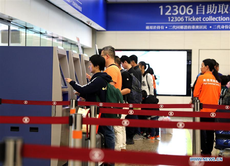 Passengers take their tickets from automotive ticket machines at the West Kowloon railway station in Hong Kong, south China, Jan. 25, 2019. To better serve the passengers using the automotive ticket machines, blue signs are installed and staff members in orange are dispatched to offer help at the West Kowloon railway station in Hong Kong. (Xinhua/Wu Xiaochu)